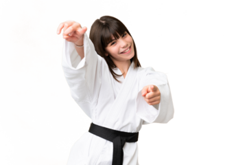 Little Caucasian girl doing karate over isolated background points finger at you while smiling