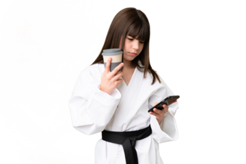Little Caucasian girl doing karate over isolated background holding coffee to take away and a mobile