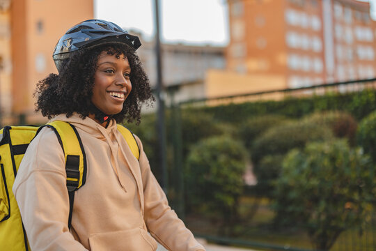 Happy delivery woman wearing helmet standing with backpack