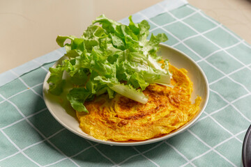 Omelette on dish with topping vegetable