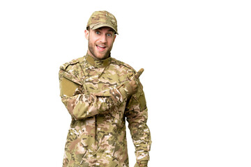 Military man over isolated chroma key background surprised and pointing side