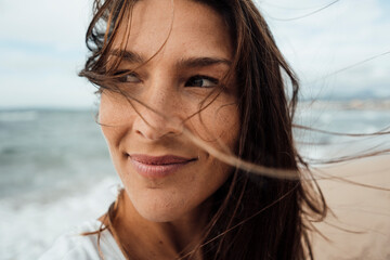 Thoughtful woman smiling at beach