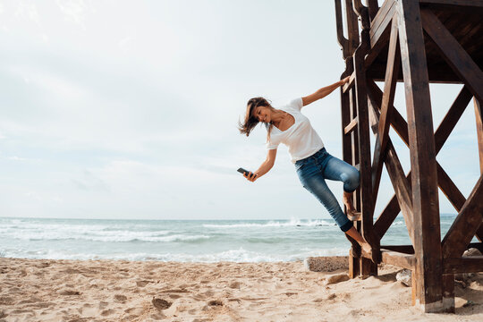 Woman Using Smart Phone And Enjoying Vacation At Beach