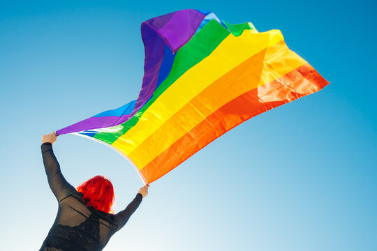 Woman on her back with open arms waving an lgbt flag