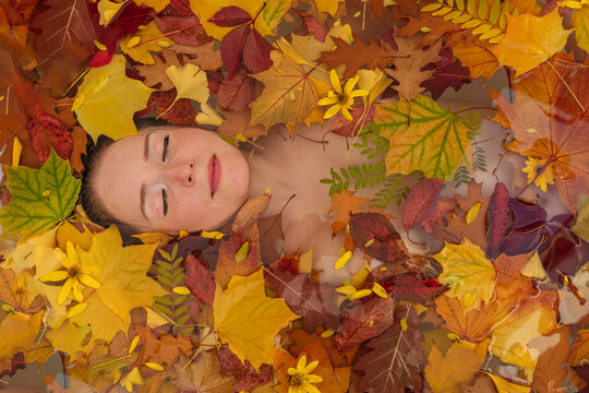 Woman relaxing with autumn leaves in water