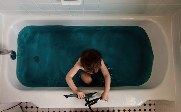 Bird's eye view of boy in bathtub playing with whales