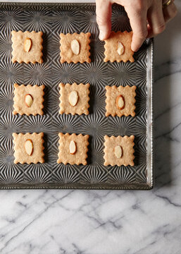 overhead shot of hand grabbing almond cookie from tray