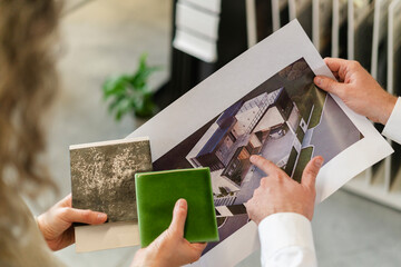 Two colleagues holding printout of a house and tile samples in architect's office