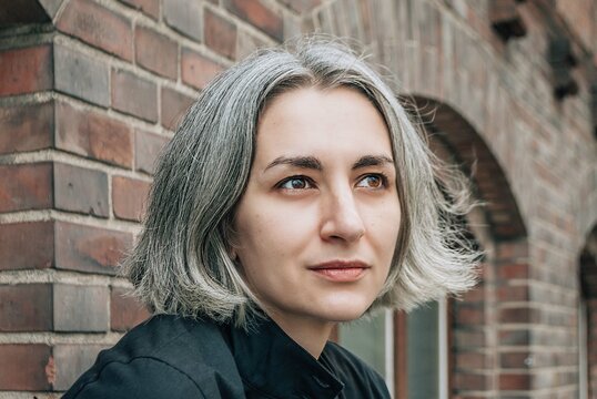 Gray-haired woman looks away on brick building backround