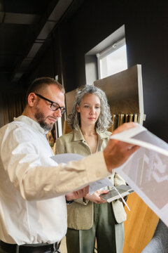 Two colleagues holding printout of a house in architect's office