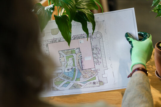 Woman wearing garden glove holding plan of garden