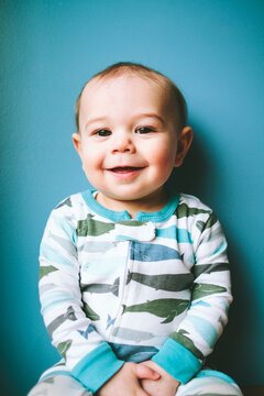 Portrait of a baby boy in narwhal pajamas against a blue wall