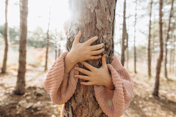Girl hugging tree trunk in forest