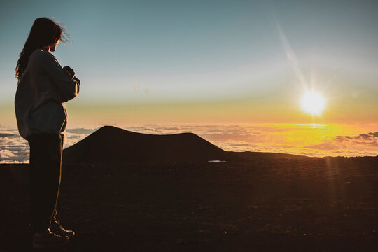 female watches sunset on top of Mauna Kea