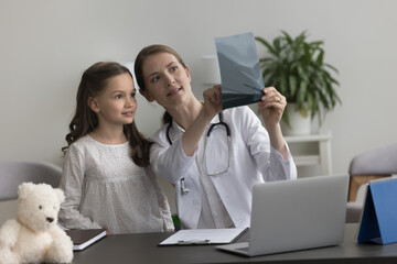 Positive pediatrician woman showing Xray scan, shot of bones, radiography screening films to little...