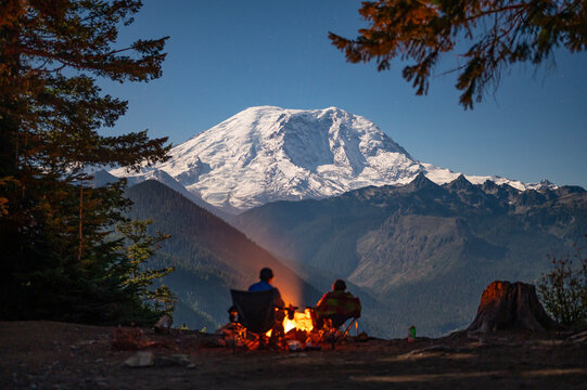 Silhouetted campers around the fire with Mount Rainier behind