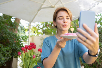 Woman with cake celebrating birthday on video call
