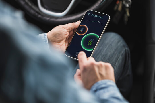 Mature woman operating electric car through mobile app on smart phone