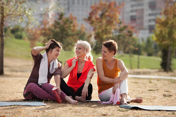 Active elderly women on fitness training in public park, relaxing and talking after workout. Happy...