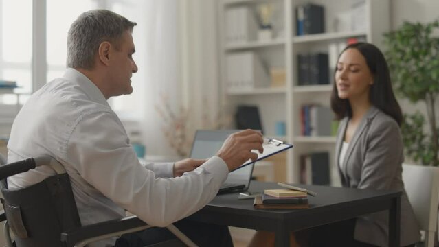 Woman candidate showing CV to male job interviewer with disability, career
