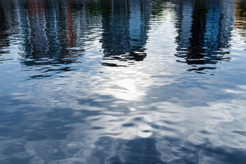 Reflection of residential district buildings on river water surface on overcast summer day