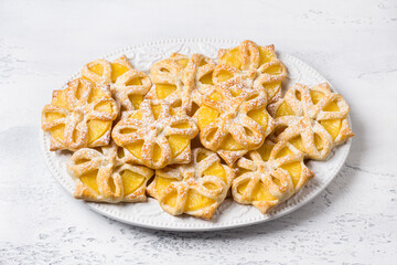 Baked pineapples in puff pastry sprinkled with powdered sugar on a light blue background, top view. Delicious homemade puffs