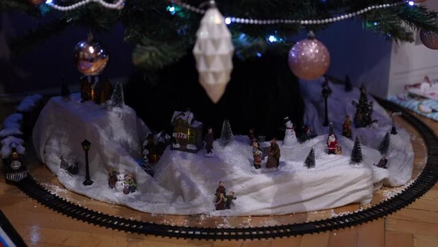 Toy train going around in circles under the decorated Christmas tree