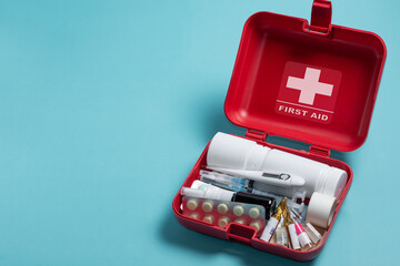 Home first aid kit on a blue background. The elements of the first aid kit are laid out on the table.