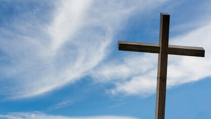 Jesus Christ cross. Easter, resurrection concept. Christian wooden cross on a background with dramatic lighting, colorful mountain sunset, dark clouds and sky, sunbeams.