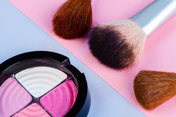 Close up of round eyeshadow palette with brushes. Cosmetic makeup accessories.