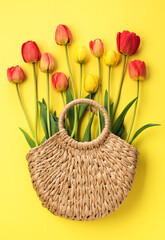 Beautiful flowers tulips in a basket on a yellow background, top view