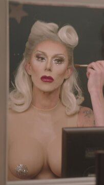 Drag Queen applying Make-up Backstage and looking in Mirror before Performance