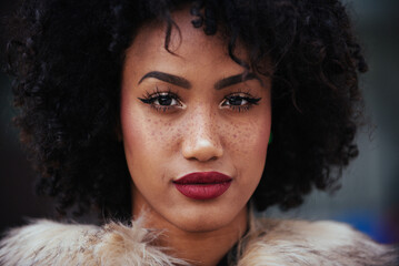 Beautiful black young woman with afro hair style and fashionable clothes strolling in the city