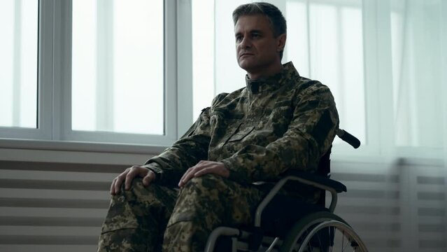 Sad soldier in wheelchair after injury alone in room of rehabilitation center