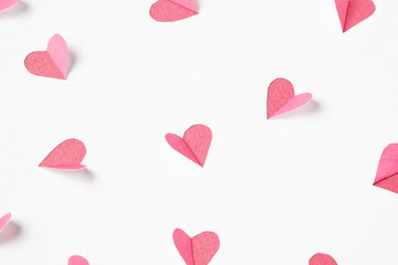 Pink hearts cut out from white paper. Festive background for valentine's day.