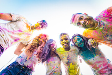 Multiethnic group of happy playful friends playing and having fun with holi colorful powder at the...