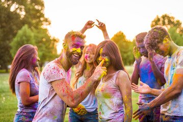 Multiethnic group of happy playful friends playing and having fun with holi colorful powder at the...