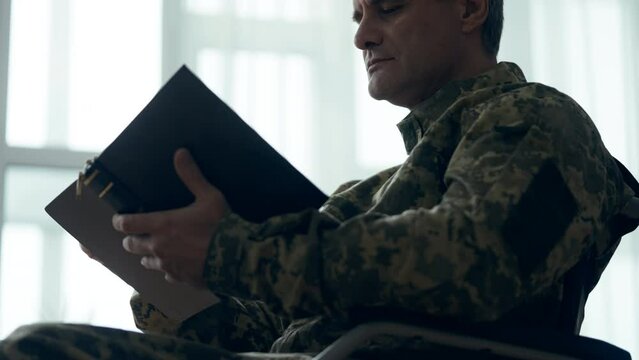 Injured chaplain in wheelchair reading Bible book, prayer and hope, religion
