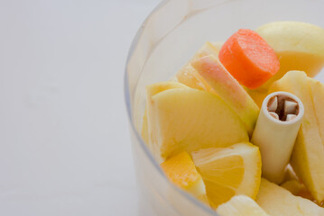 Macro shot of fresh sliced lemon, apple and carrot in blender