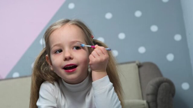 Little girls have fun make-up using brush apply shiny shadows on eyelids beauty