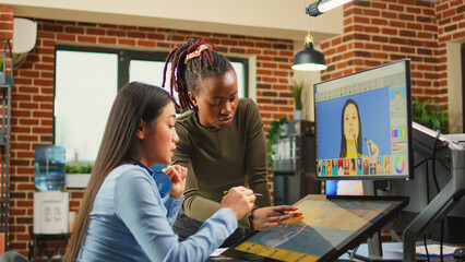 Team of diverse colorists editing pictures with retouching interface, working on photo color...