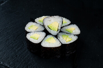 Traditional Japanese kitchen set of sushi rolls with avocado, rice and nori.