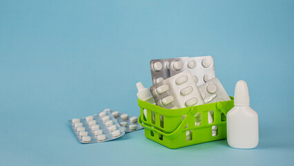A shopping basket with medicines and pharmacy supplies. Medications and pills on a blue background. The concept of online shopping,  online store, pharmacy chains. Banner, copy space for text