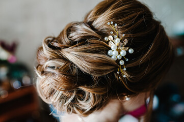 Luxury. Rich Stylish Brunette with Pearly Beads. Elegant Style. Close-up shot of female hair-do made as a strand of hair fixed with a gold hair clip. © Serhii