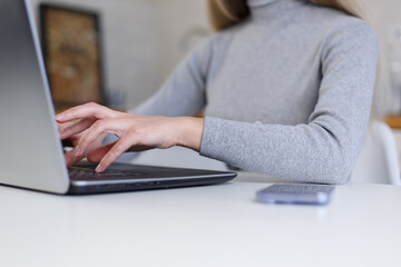 Young woman typing code on modern laptop computer at home. Female programmer person working online