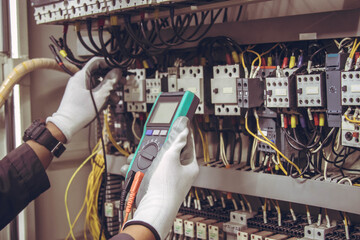 Electrician engineer tests electrical installations and wires on relay protection system.