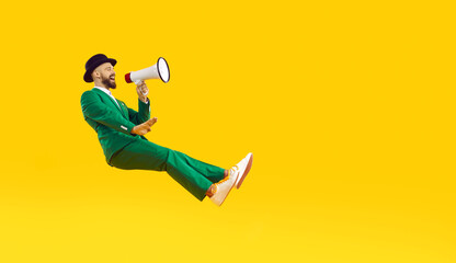 Cheerful positive man with loudspeaker announcing crazy discounts for St. Patrick's Day. Man in...