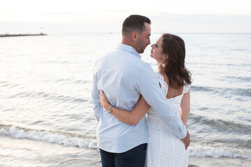 romantic couple embracing and looking at each other smiling at ocean