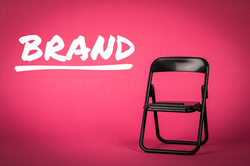 BRAND, business concept. Black chair on a pink background