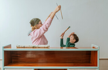 An adult mom and her teenage son have fun painting an antique piece of furniture.